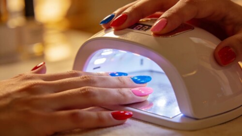 Nail technician using an LED nail curing lamp for gel polish on a client's nails
